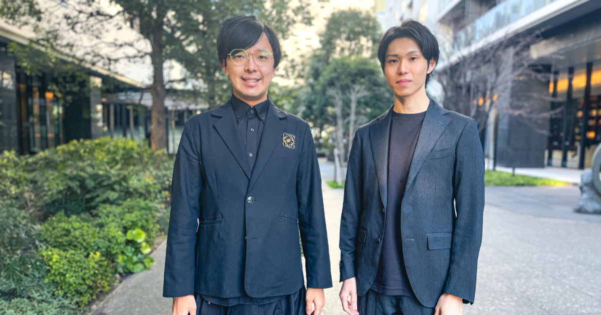 顧問契約のお知らせに掲載された屋外に並ぶ2人の写真